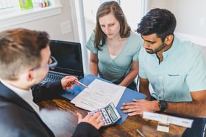 Underwriter in Black Coat Discussing an Ownership Agreement to a Couple Inside the Office