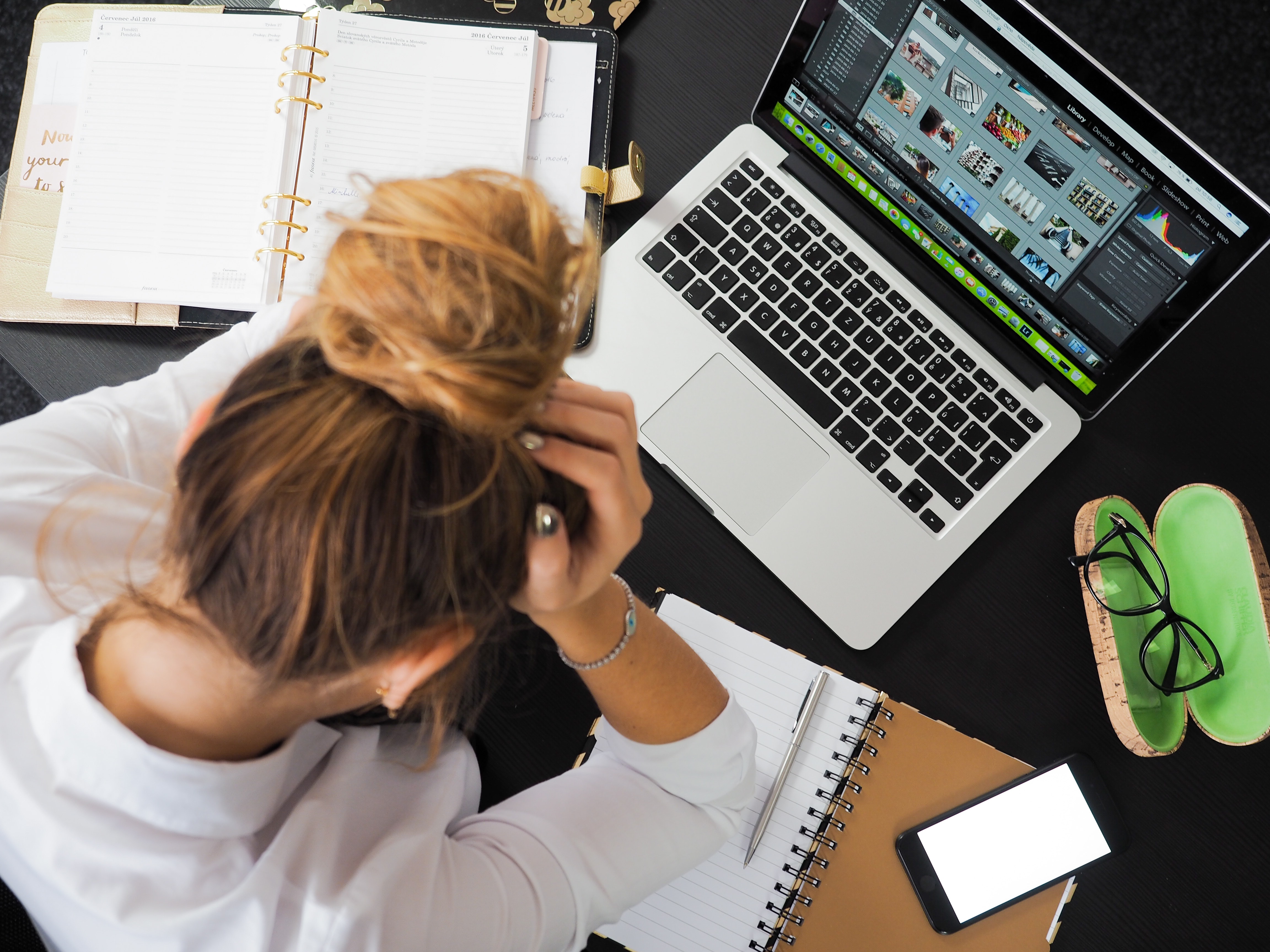 Stressed woman working on laptop in office.