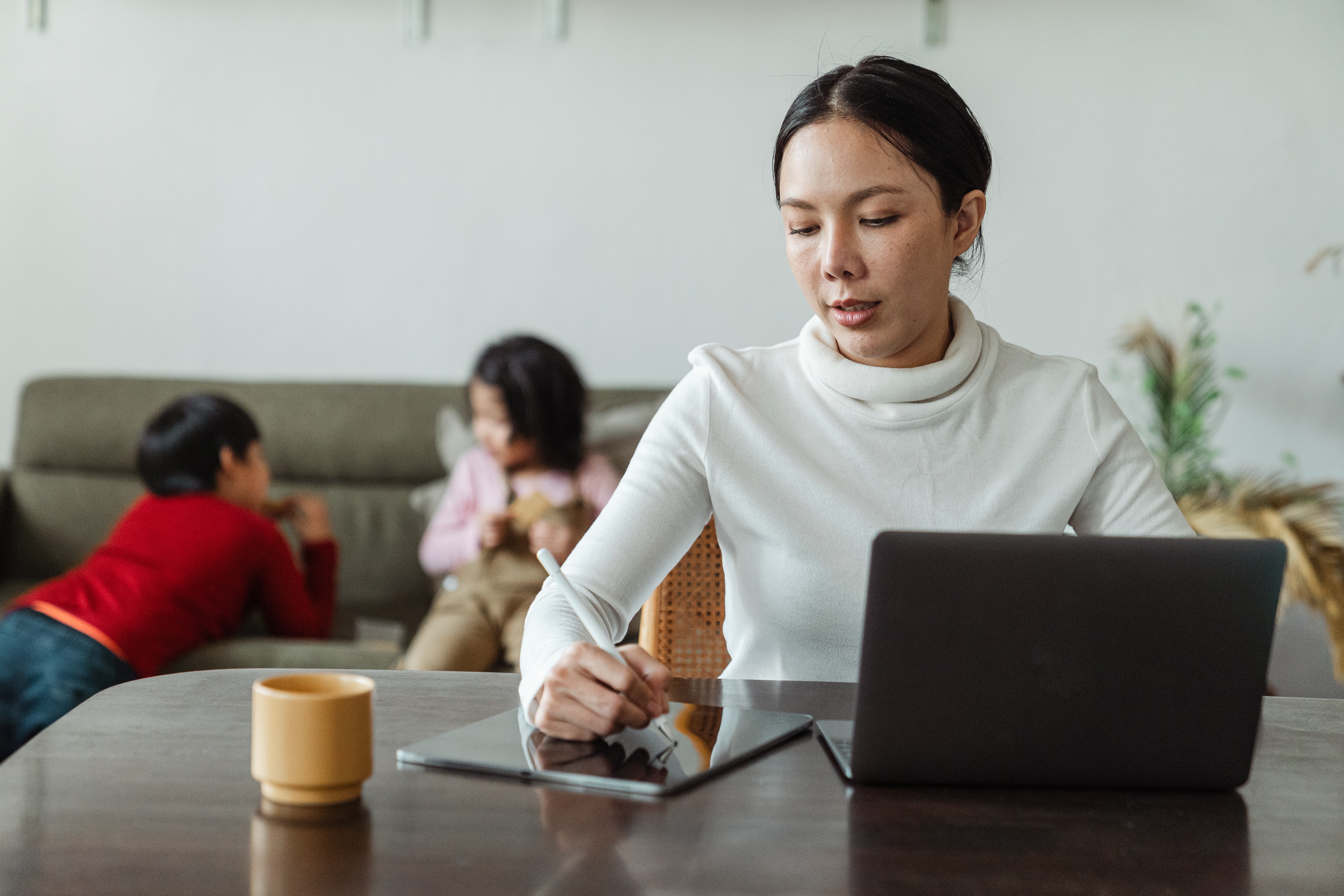 mother working remotely while children playing on sofa